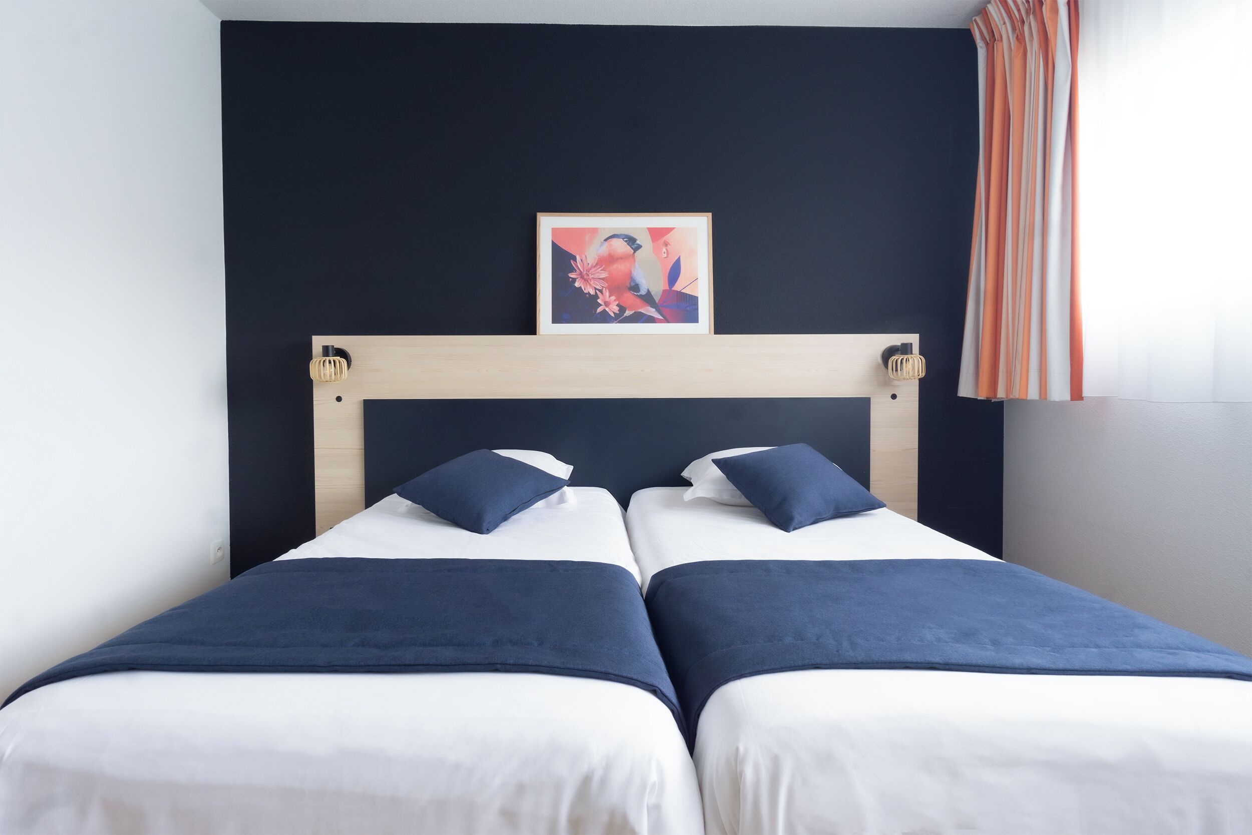 A double bed with a wooden headboard, two pillows, and a framed artwork above.