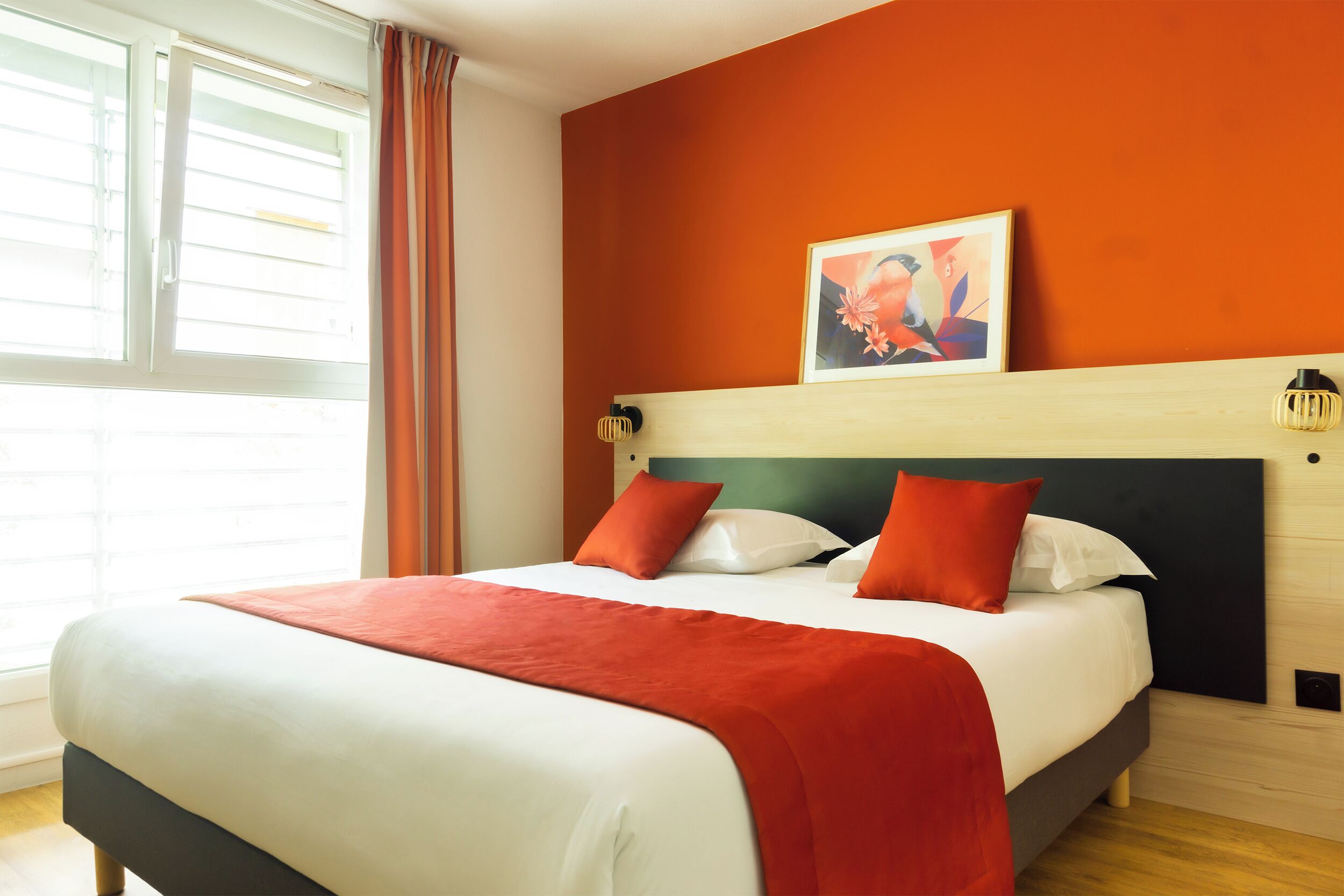 Una habitación de hotel con cama, un cuadro en la pared y una ventana con cortinas.