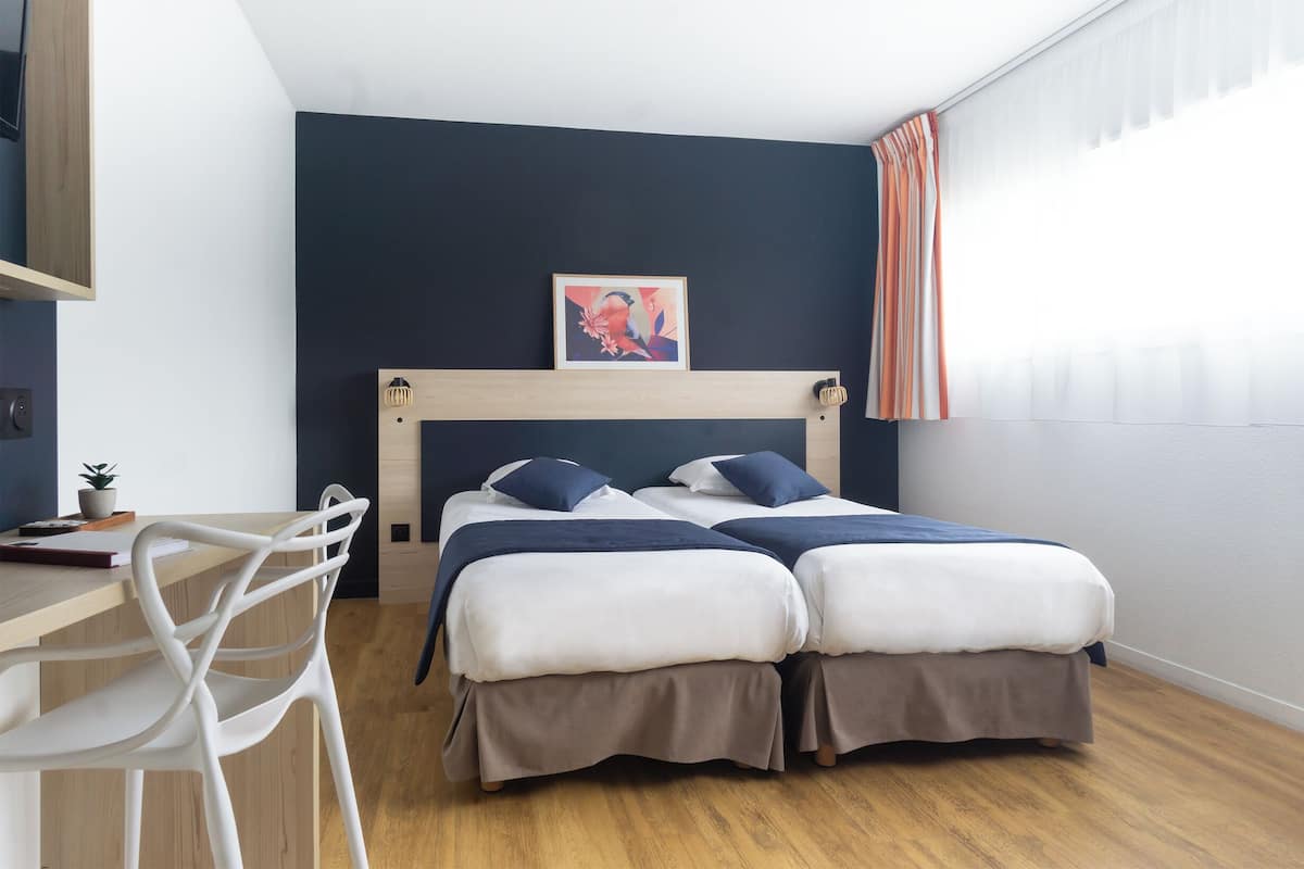 A bedroom with a bed, a desk, and a chair.