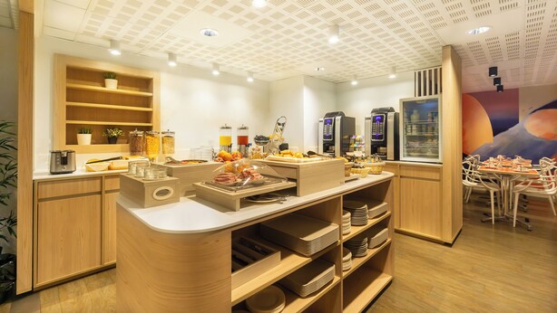 A breakfast buffet area with wooden shelves, a coffee machine, and a variety of food items. - City Résidence Bordeaux Centre (Bordeaux)