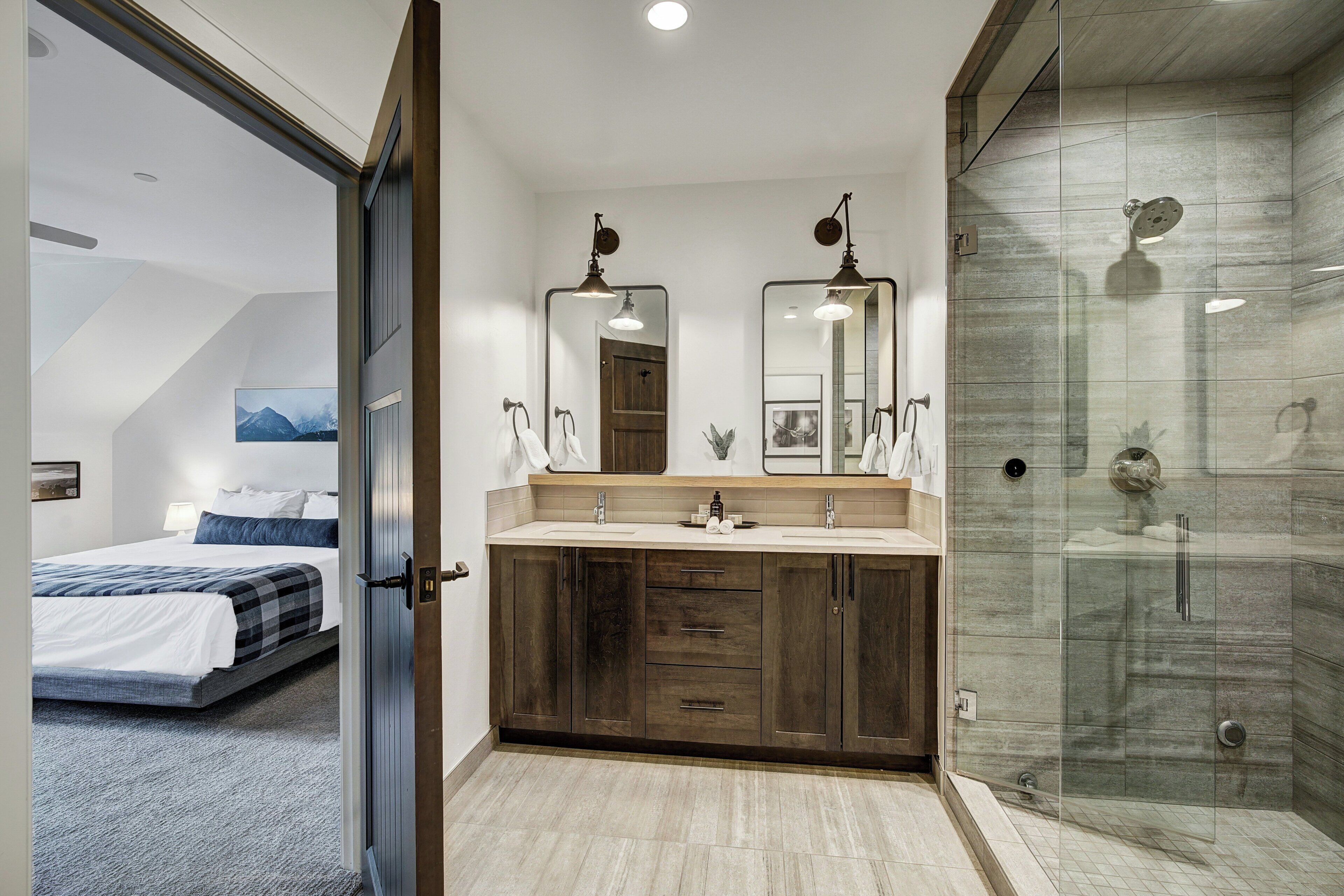 A modern bathroom with a shower, a double sink vanity, and a large mirror.