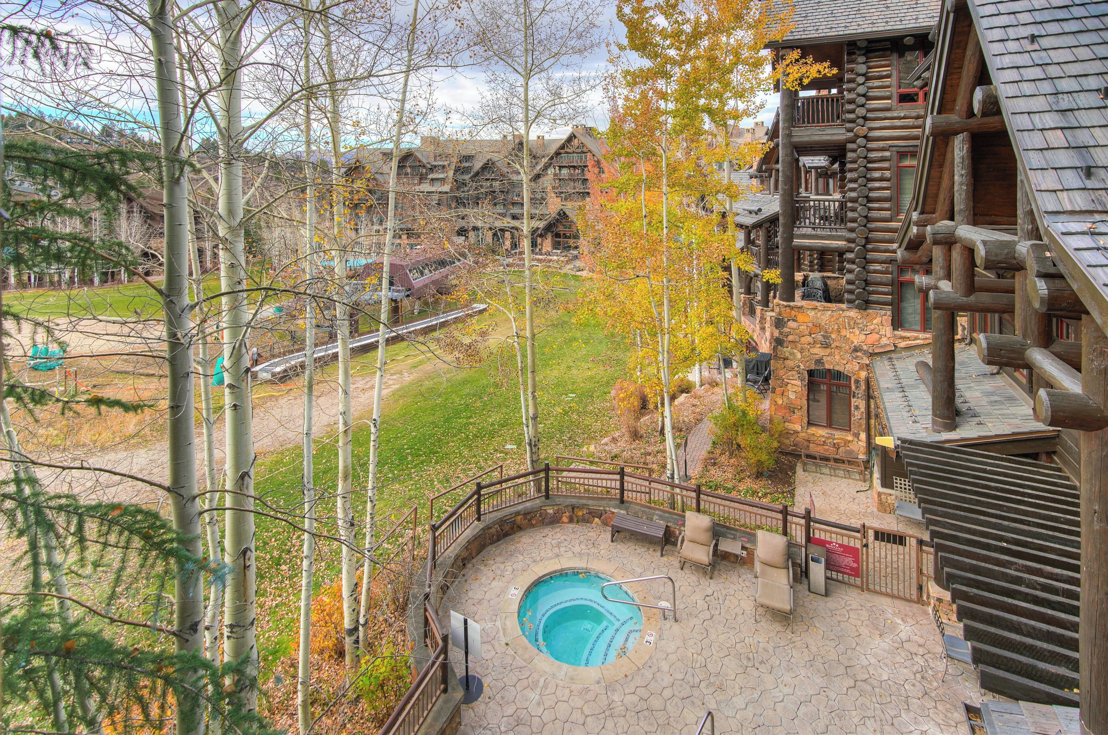 A log cabin-style building with a stone patio, a swimming pool, and a wooden deck.