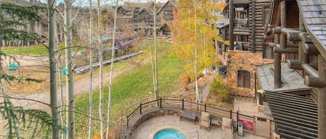 A log cabin-style building with a stone patio, a swimming pool, and a wooden deck.