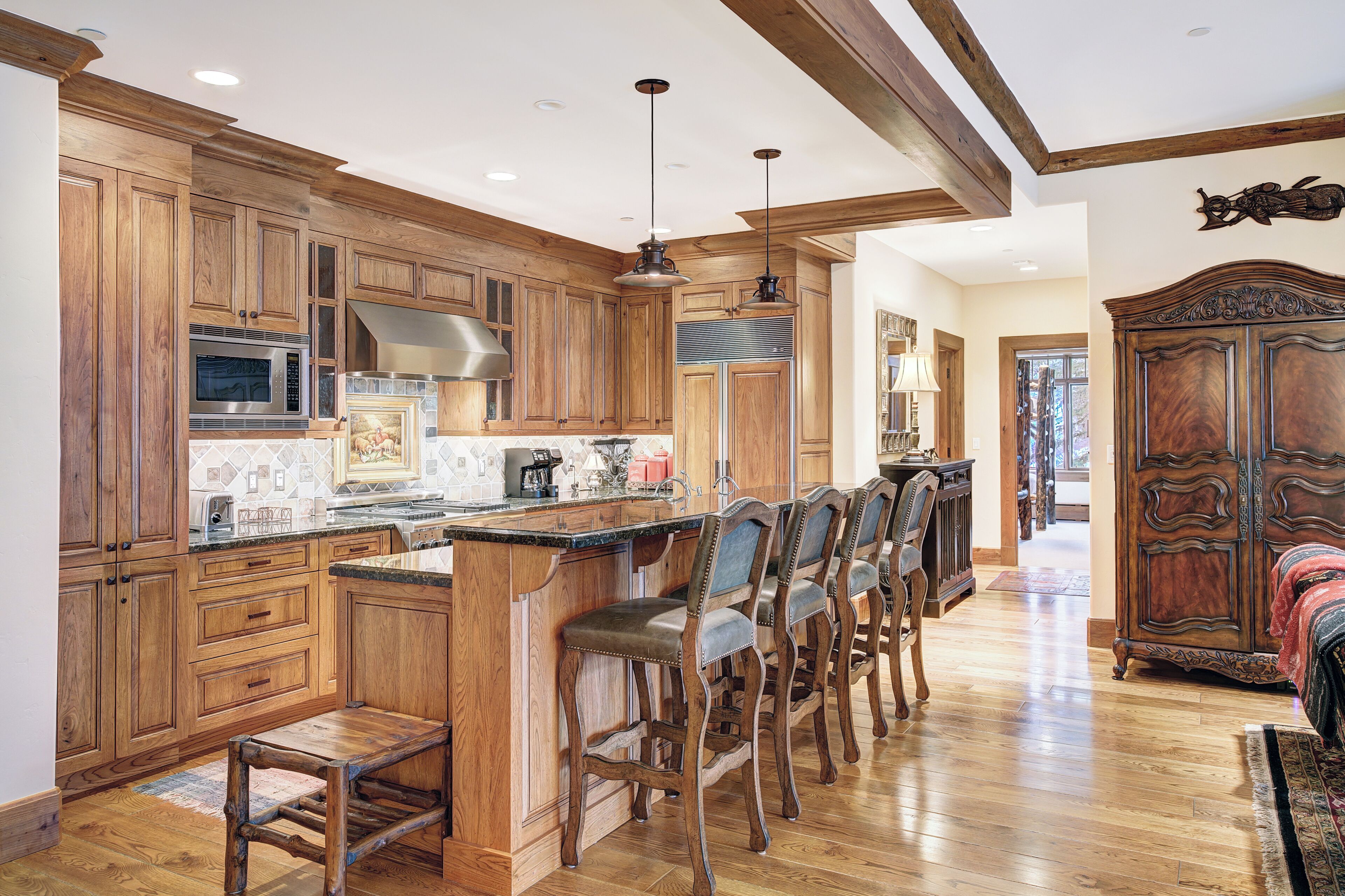 A spacious kitchen with wooden cabinets, a large island with bar stools, and a built-in oven.