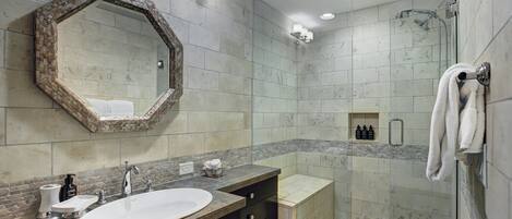 Ein modernes Badezimmer mit großem Spiegel, Waschbecken, Dusche und Handtuchhalter.