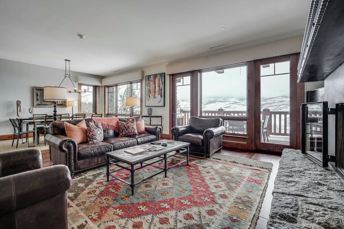A spacious living room with a large window, a fireplace, and a dining area.