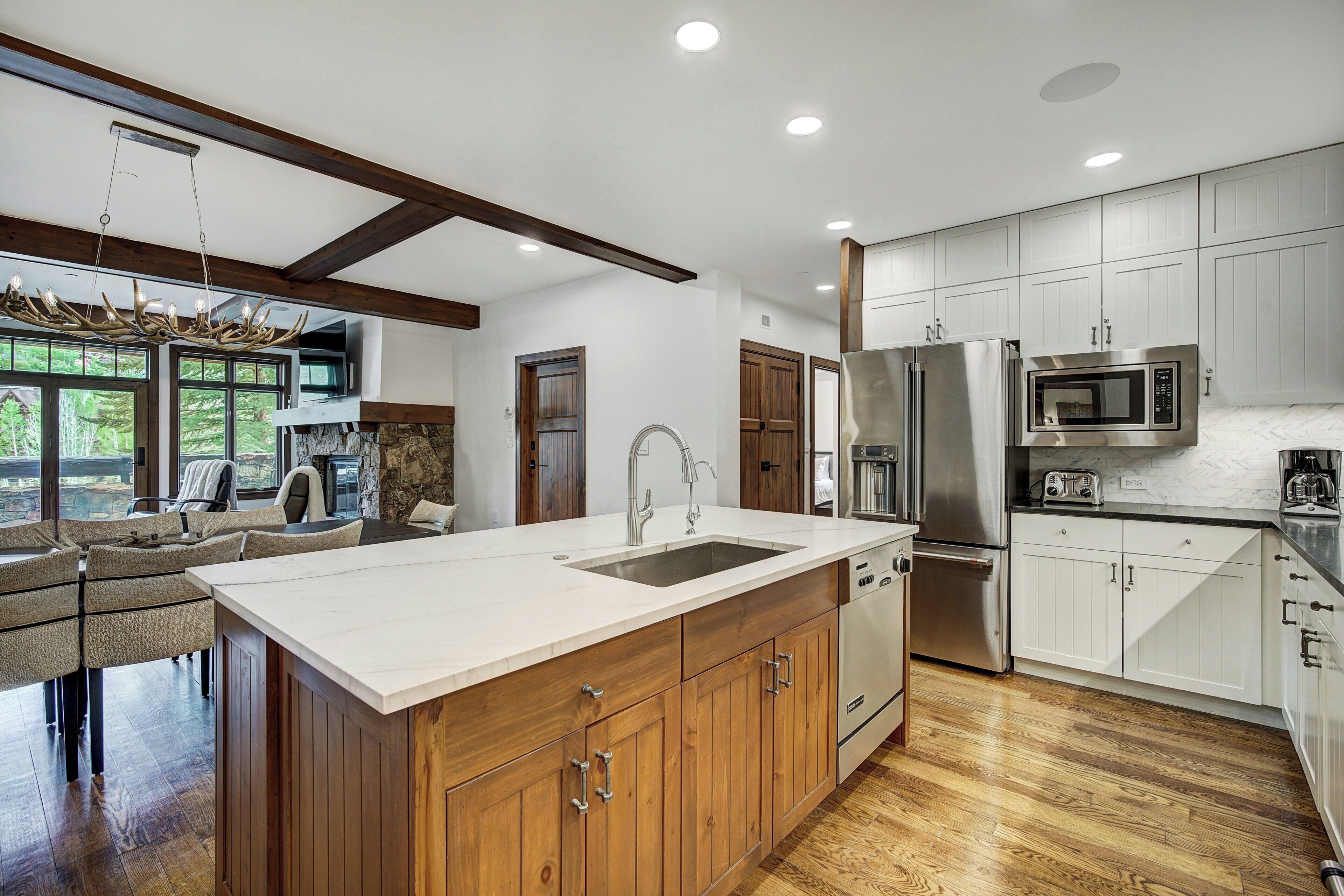 A modern kitchen with a large island, stainless steel appliances, and wooden cabinets.