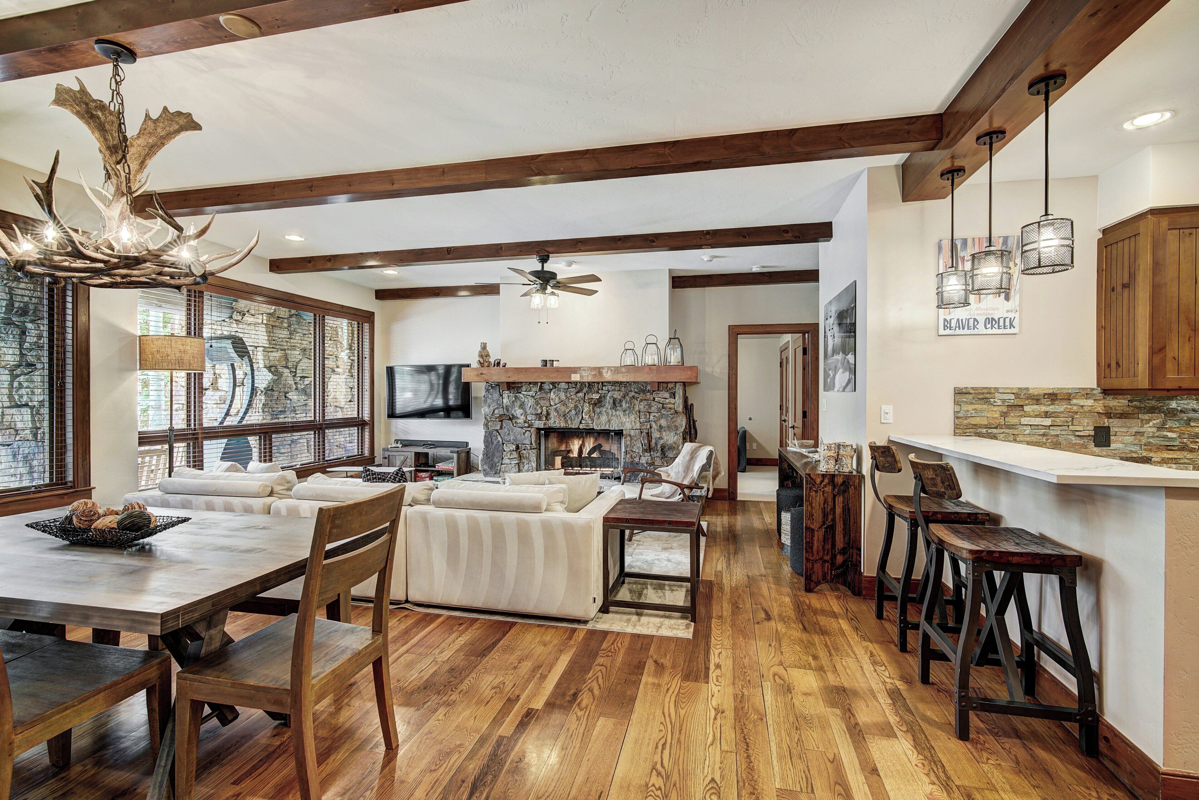 A spacious living room with a fireplace, wooden flooring, and a dining area with a large table and chairs.