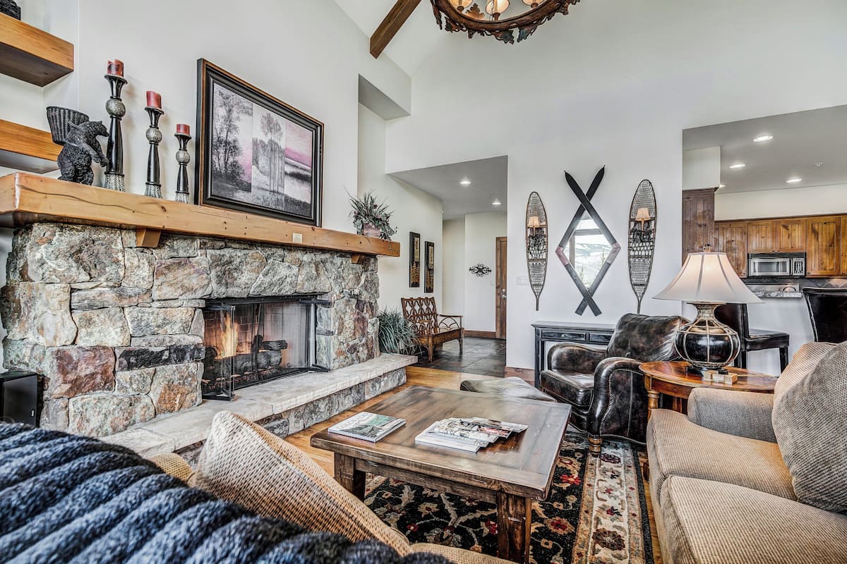 A cozy living room with a stone fireplace, wooden shelves, and a comfortable seating area.