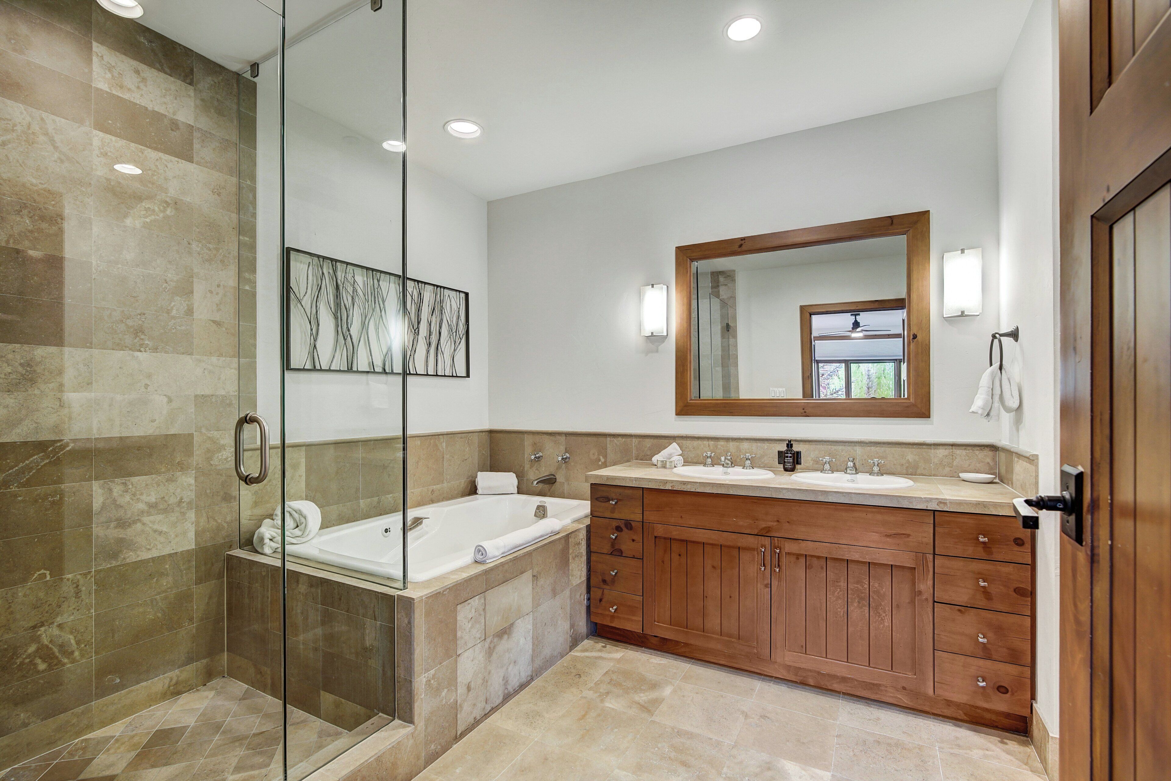 Un bagno moderno con doccia vetrata, lavabo doppio e un ampio specchio sopra il mobile.