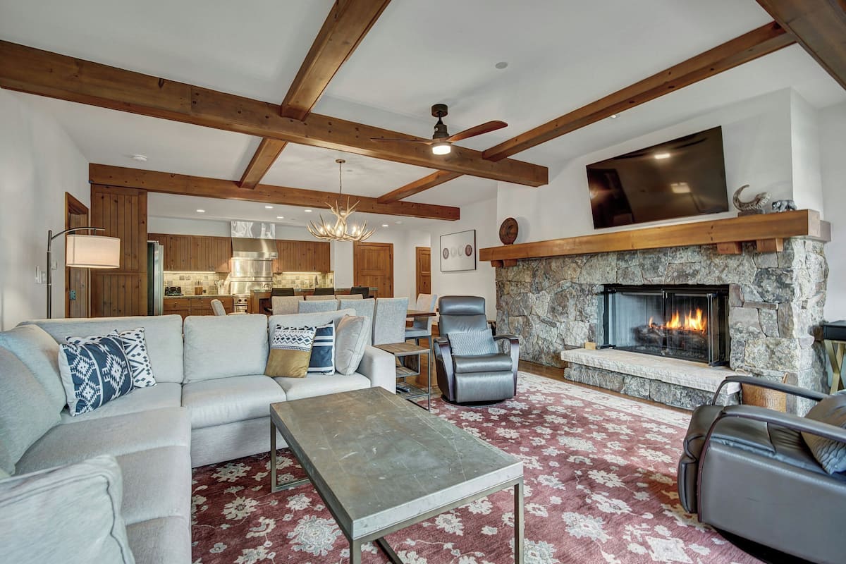 A spacious living room with a fireplace, a sofa set, a coffee table, and a stone fireplace surround.