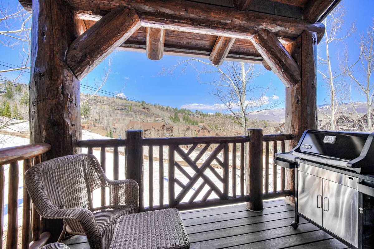 A wooden deck with a grill and wicker chairs.