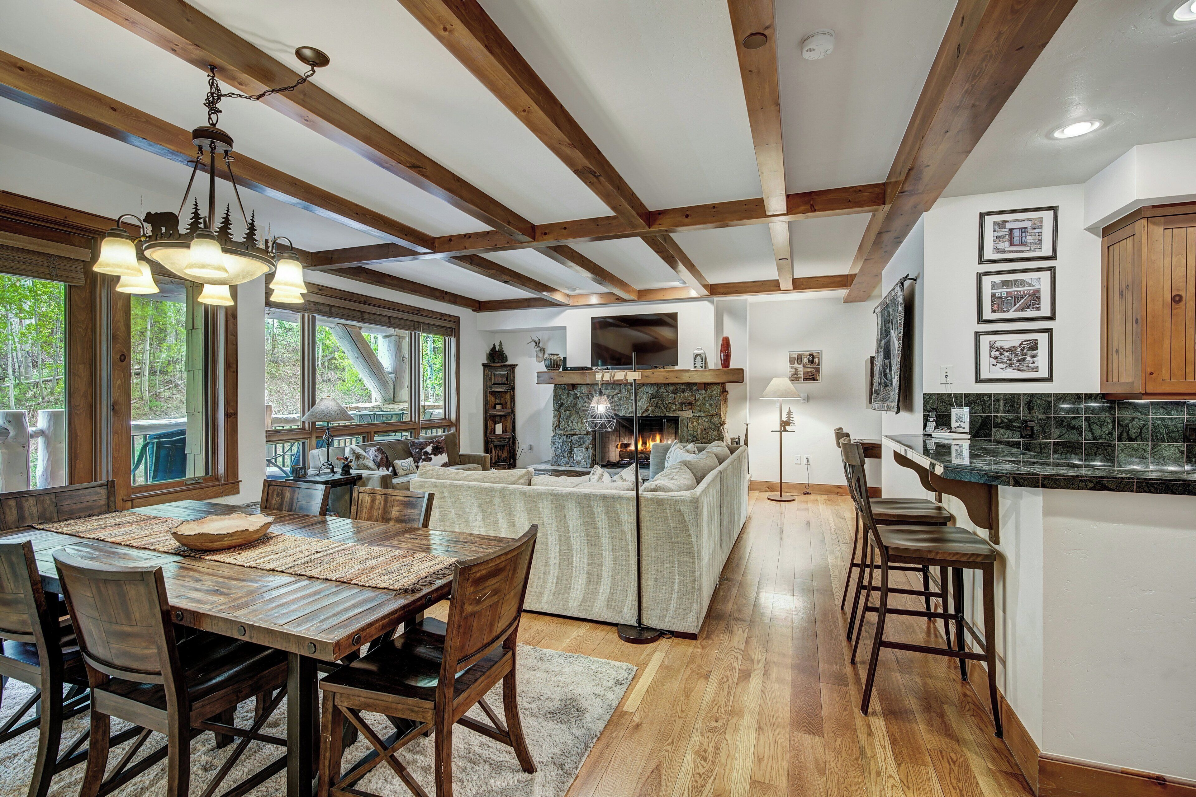 A spacious kitchen with wooden beams, a dining area with a large table and chairs, and a cozy living area with a fireplace.