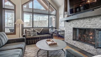 A spacious living room with a fireplace, large windows, and a cozy seating area.