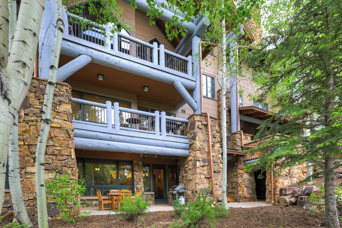 A multi-story log cabin with a stone exterior, a balcony, and a patio area with outdoor seating.
