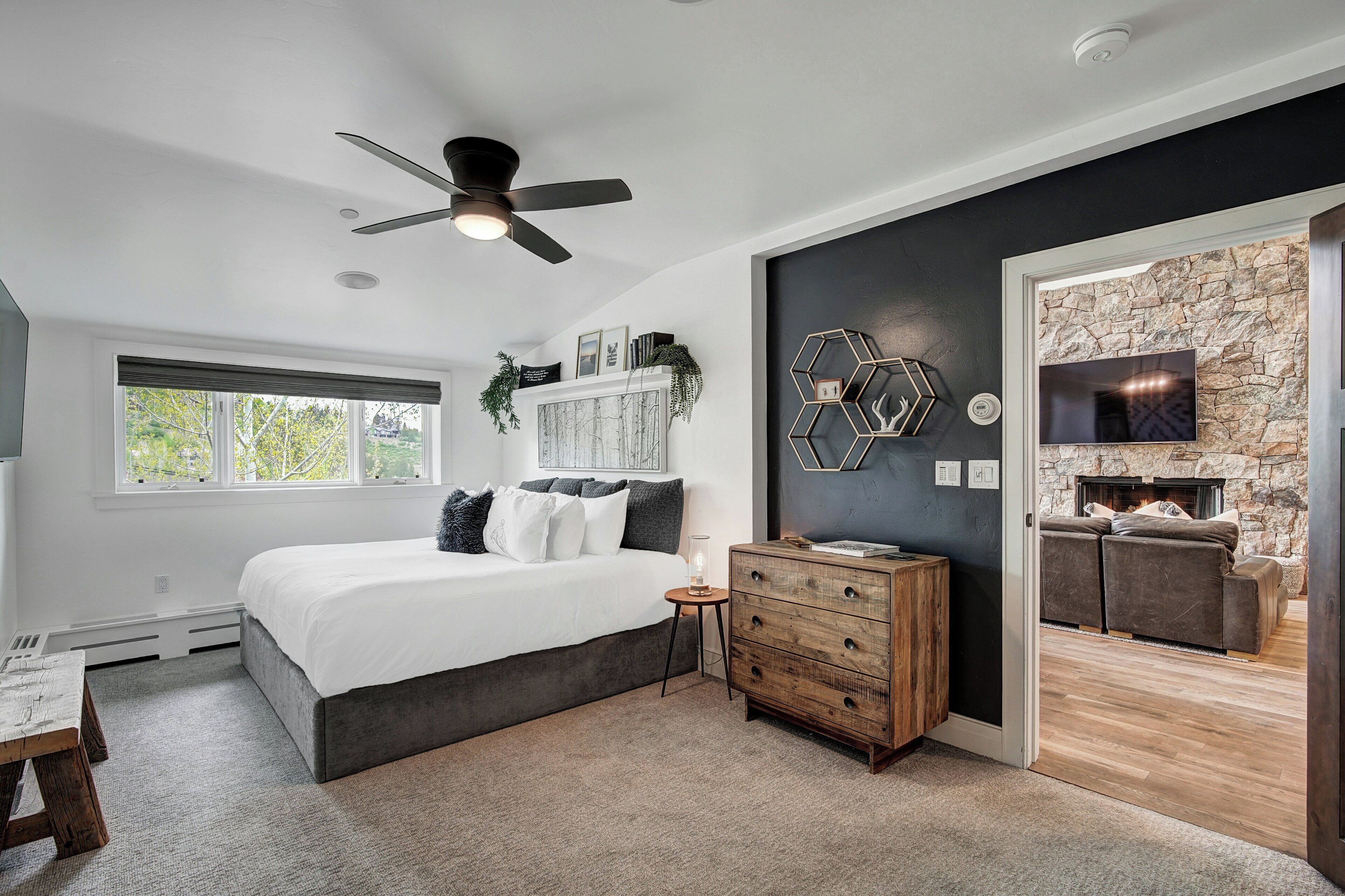 Un dormitorio con cama, cómoda y chimenea.