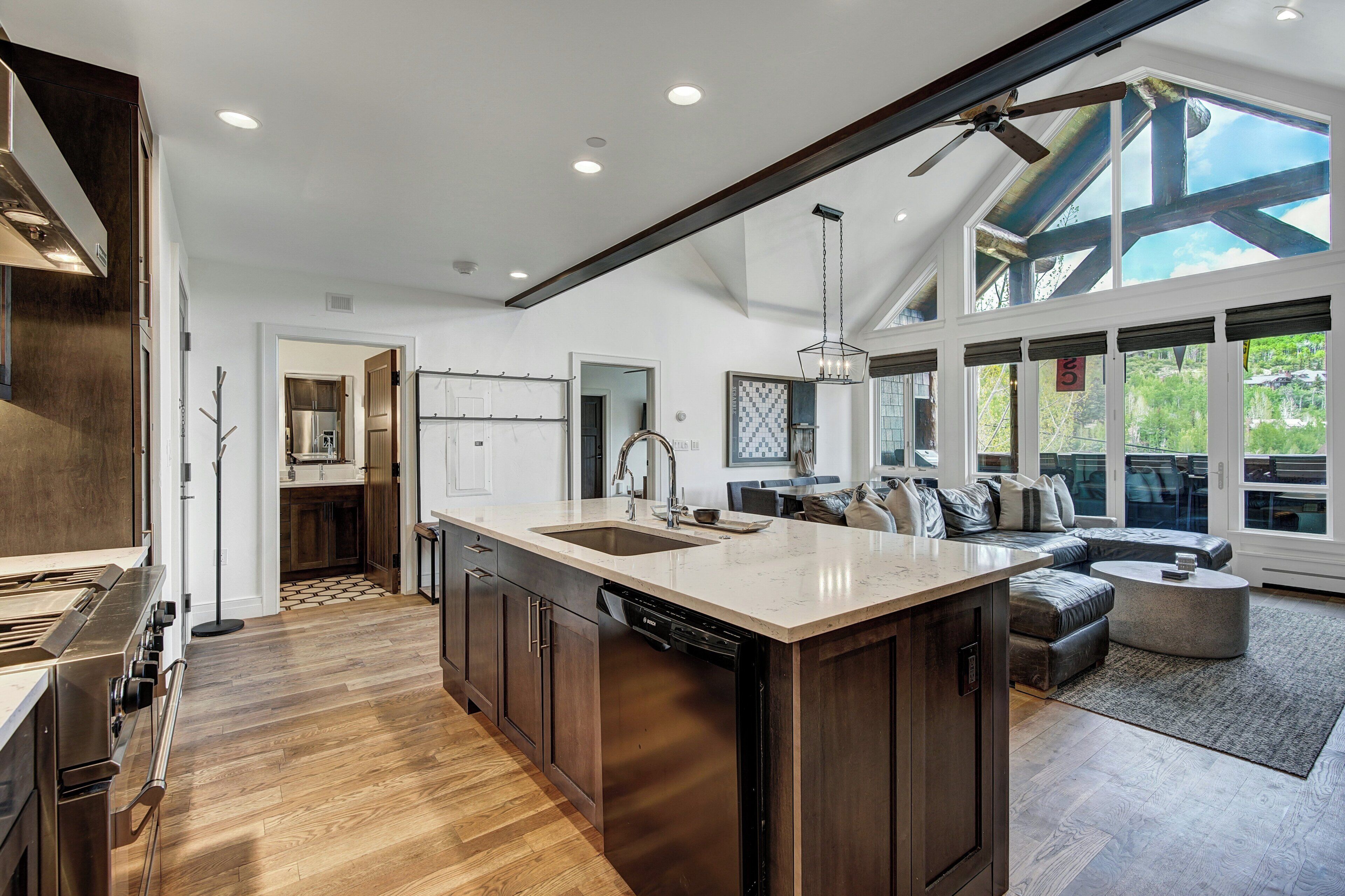 A spacious kitchen with a large island, wooden cabinets, and a dishwasher.