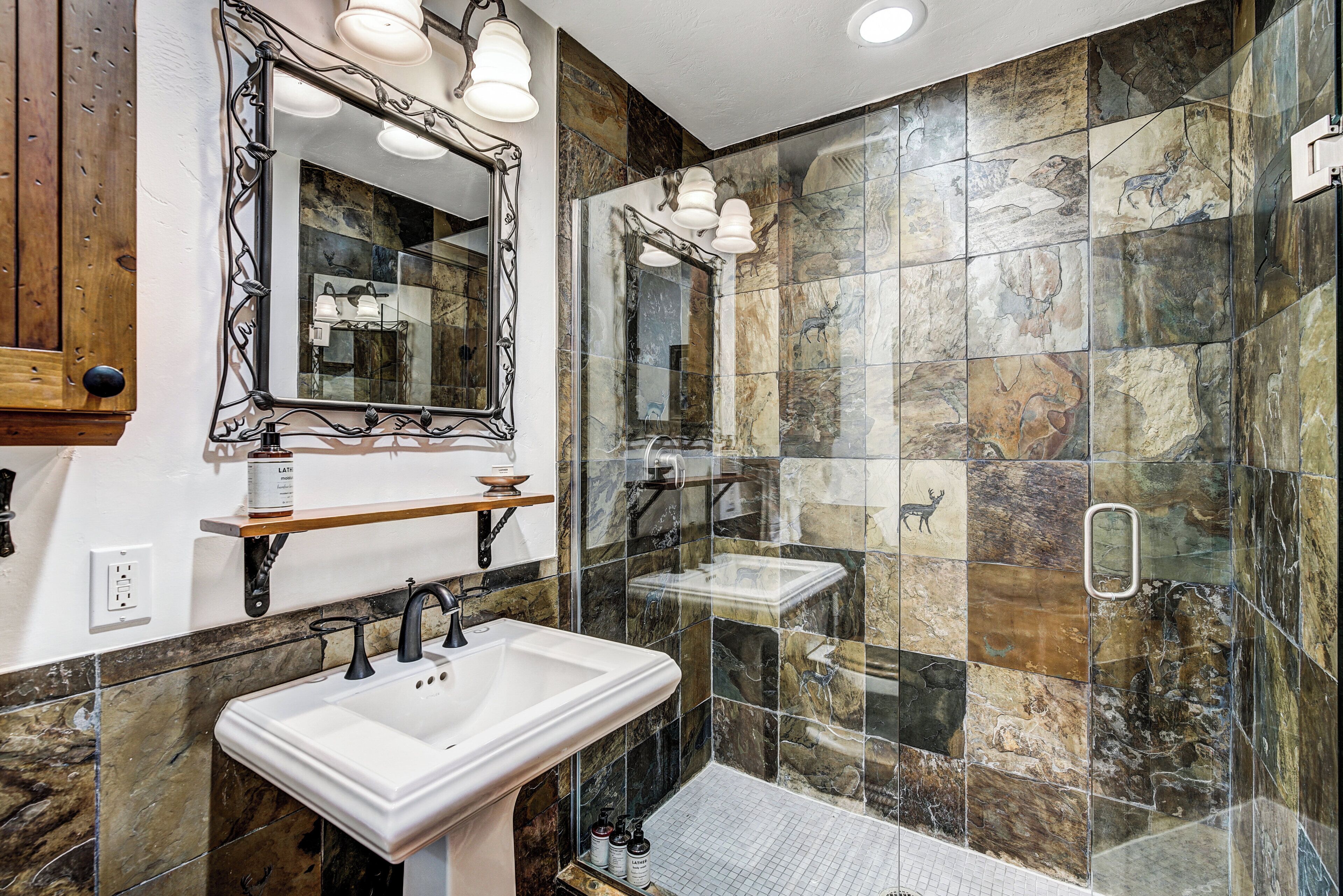 Une salle de bain avec deux lavabos, un grand miroir et une douche dotée d’une porte en verre.
