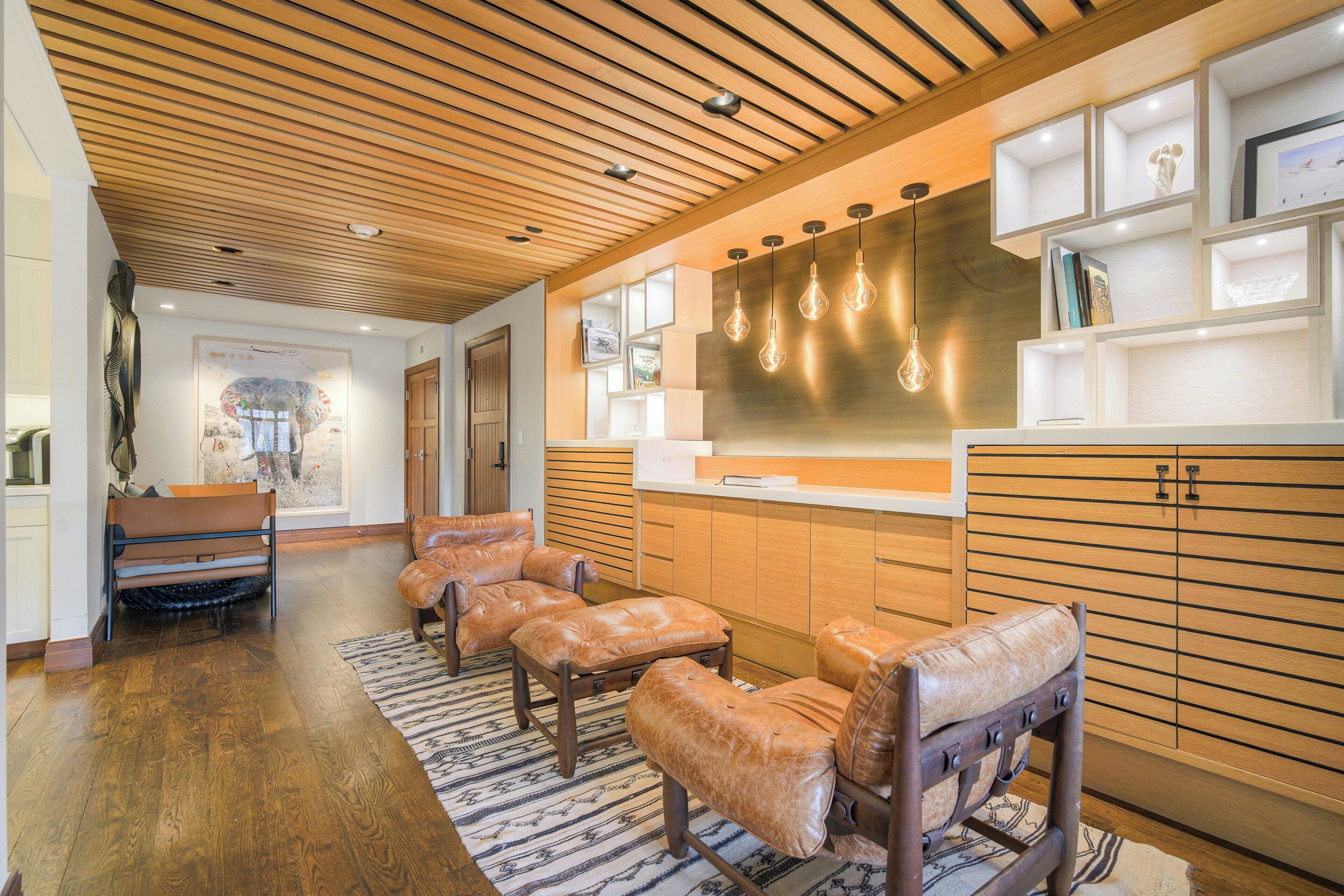 A modern interior with leather sofas, wooden flooring, and a built-in bookshelf.