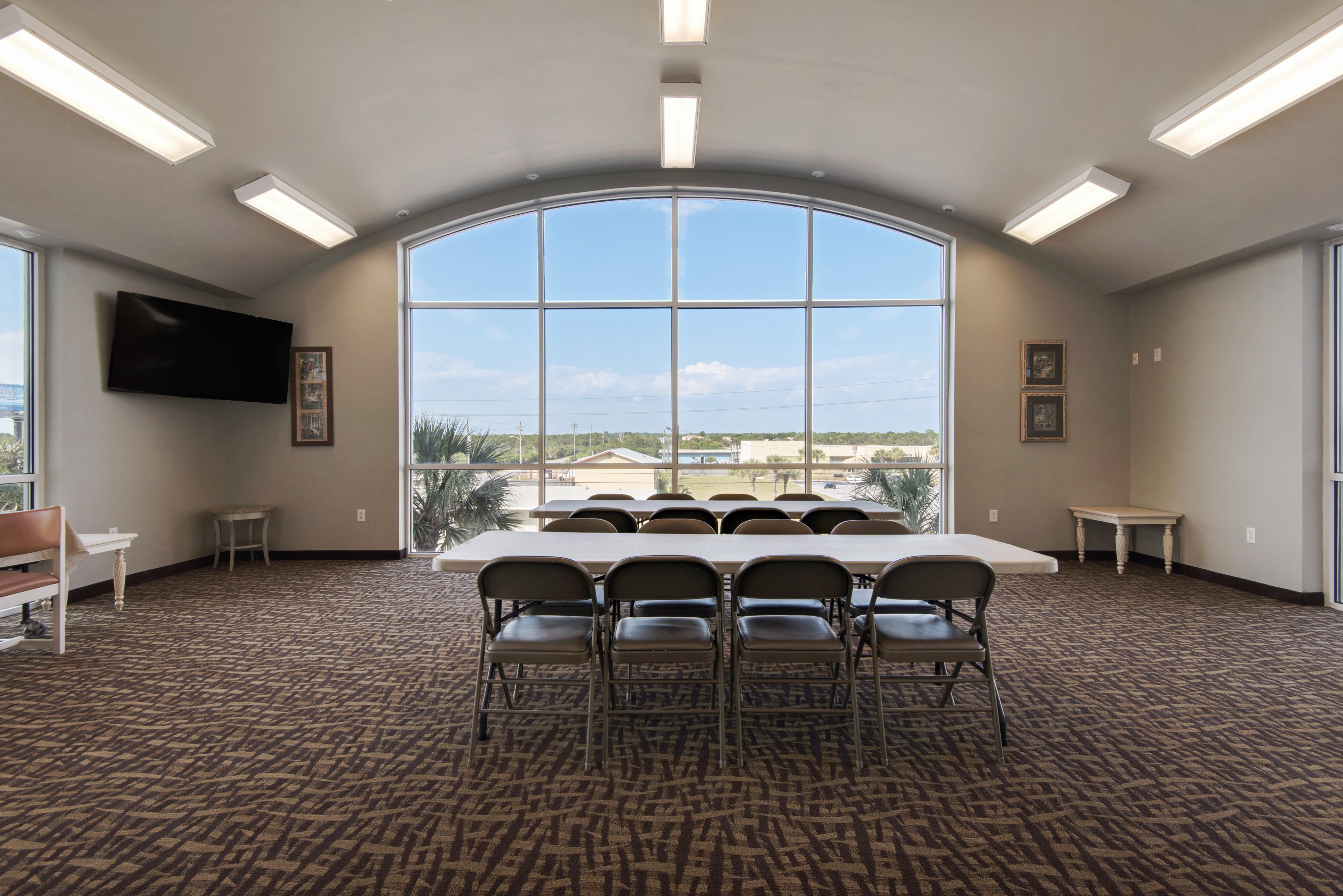 Una sala conferenze con un grande tavolo e sedie, una TV a schermo piatto e una vista attraverso un'ampia finestra ad arco.