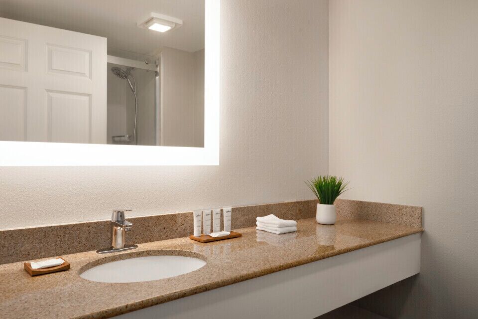 Un baño moderno con un espejo grande, un lavabo y una ducha.
