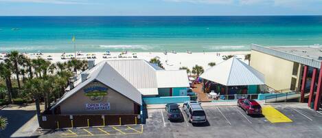 Una propiedad frente a la playa con estacionamiento, un edificio con el letrero 'Barefoot Grill' y vista a la playa y al océano.