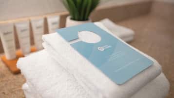 A neatly folded white towel with a blue card on top, placed on a beige surface.