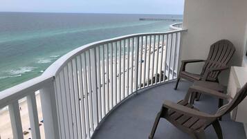 Ein Balkon mit Blick auf einen Strand und einen Steg. Zwei Stühle und ein Tisch befinden sich auf dem Balkon.