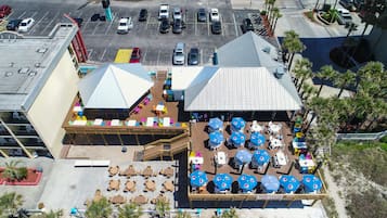 An aerial view of a hotel with outdoor seating areas, a covered deck, and a parking lot.