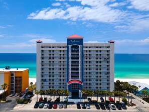 A large hotel with multiple floors, a prominent 'Radisson' sign, and a parking lot with several cars. - Radisson Beachfront Hotel - Panama City Beach (Panama City Beach)