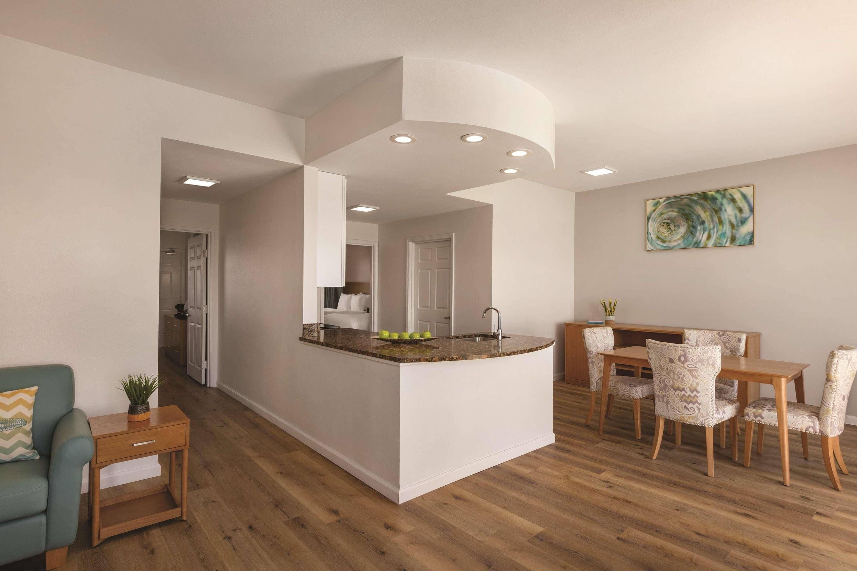 Una cocina moderna con una isla central, una mesa de comedor de madera y sillas.