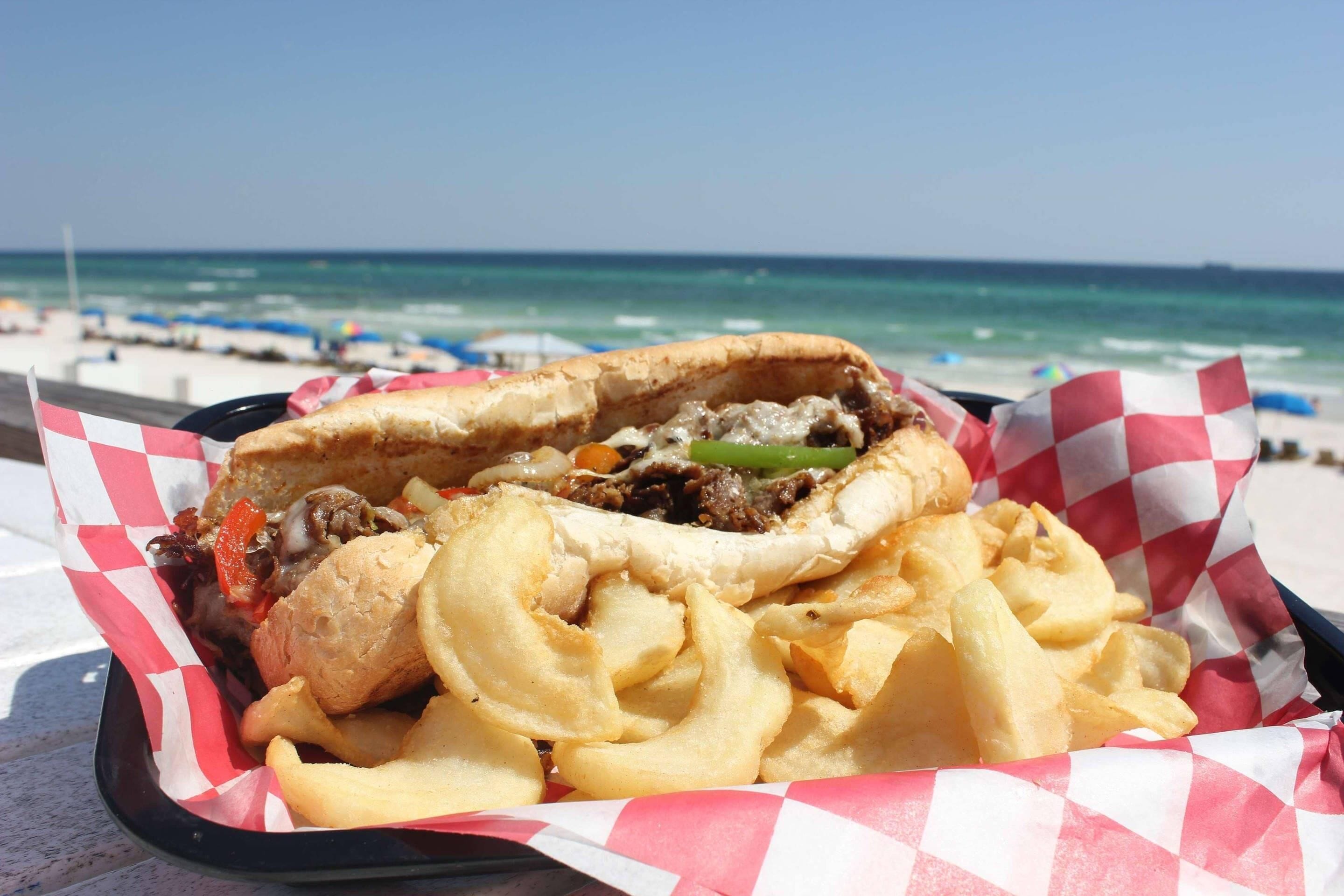 Un sandwich accompagné de frites, dégusté sur la plage.