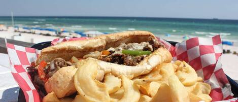 Un sandwich accompagné de frites, dégusté sur la plage.