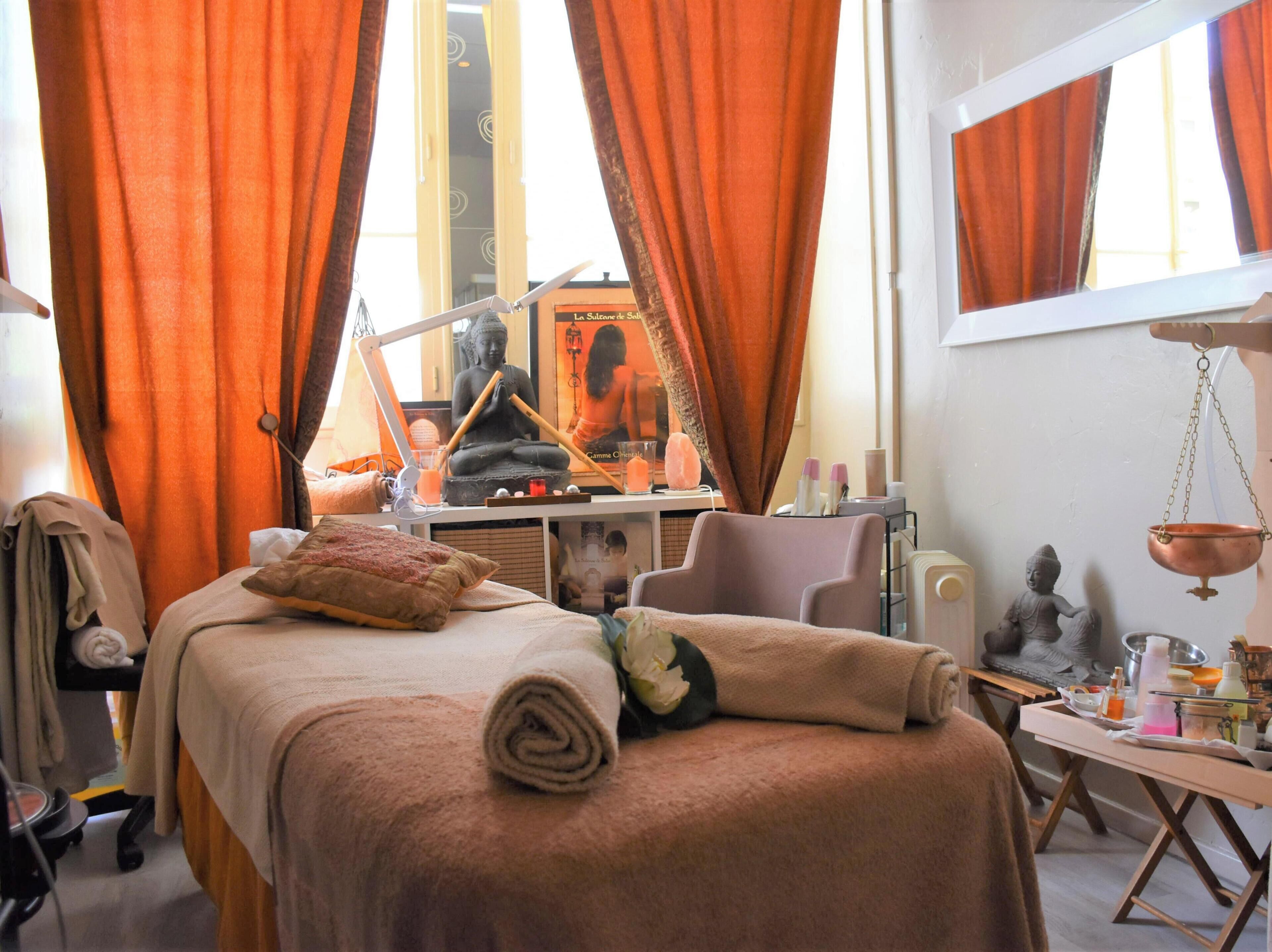 Une pièce comprenant une table de massage, une statue et un miroir qui reflète une statue de Bouddha.