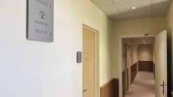 Un couloir avec une pancarte indiquant « Niveau 1, chambres 09 à 18 ».