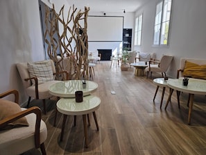 A modern lounge area with round tables, comfortable seating, and a fireplace.
