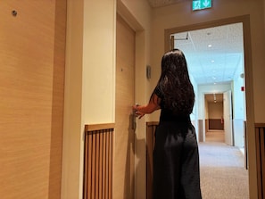 Una persona entrando por un pasillo con paneles de madera y suelo alfombrado.