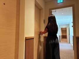 Una persona entrando por un pasillo con paneles de madera y suelo alfombrado.