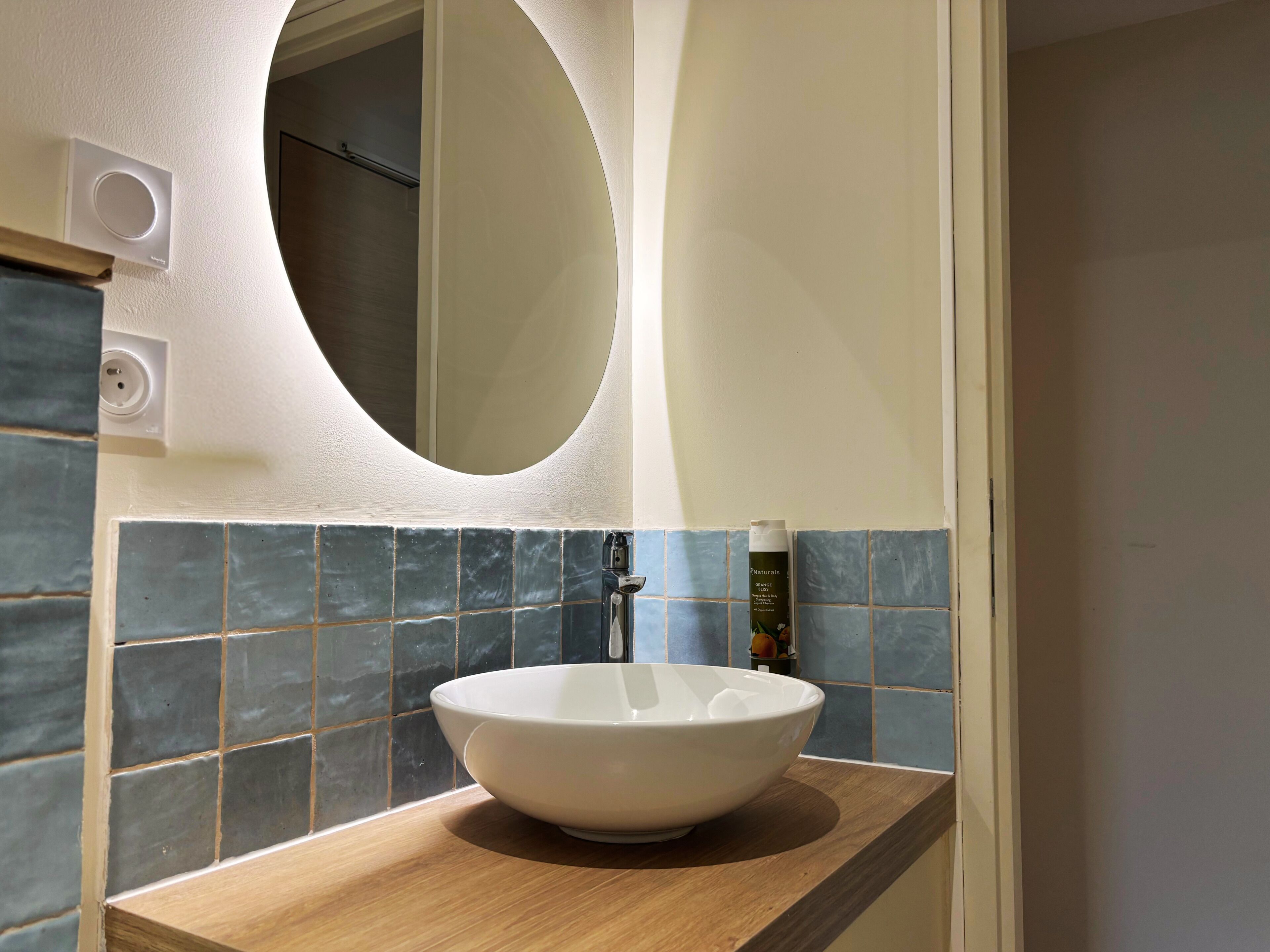 Een badkamer met een witte wastafel, een spiegel en blauwe tegels.