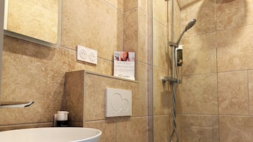 Ein Badezimmer mit einem weißen Waschbecken, einem Handtuch, einer Dusche mit Duschbrause und einem Schild an der Wand.