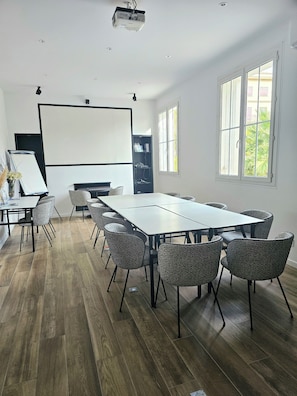 A conference room with a long table, chairs, a projector, and a screen. - Adonis Sanary Grand Hôtel des Bains (Sanary-sur-Mer)