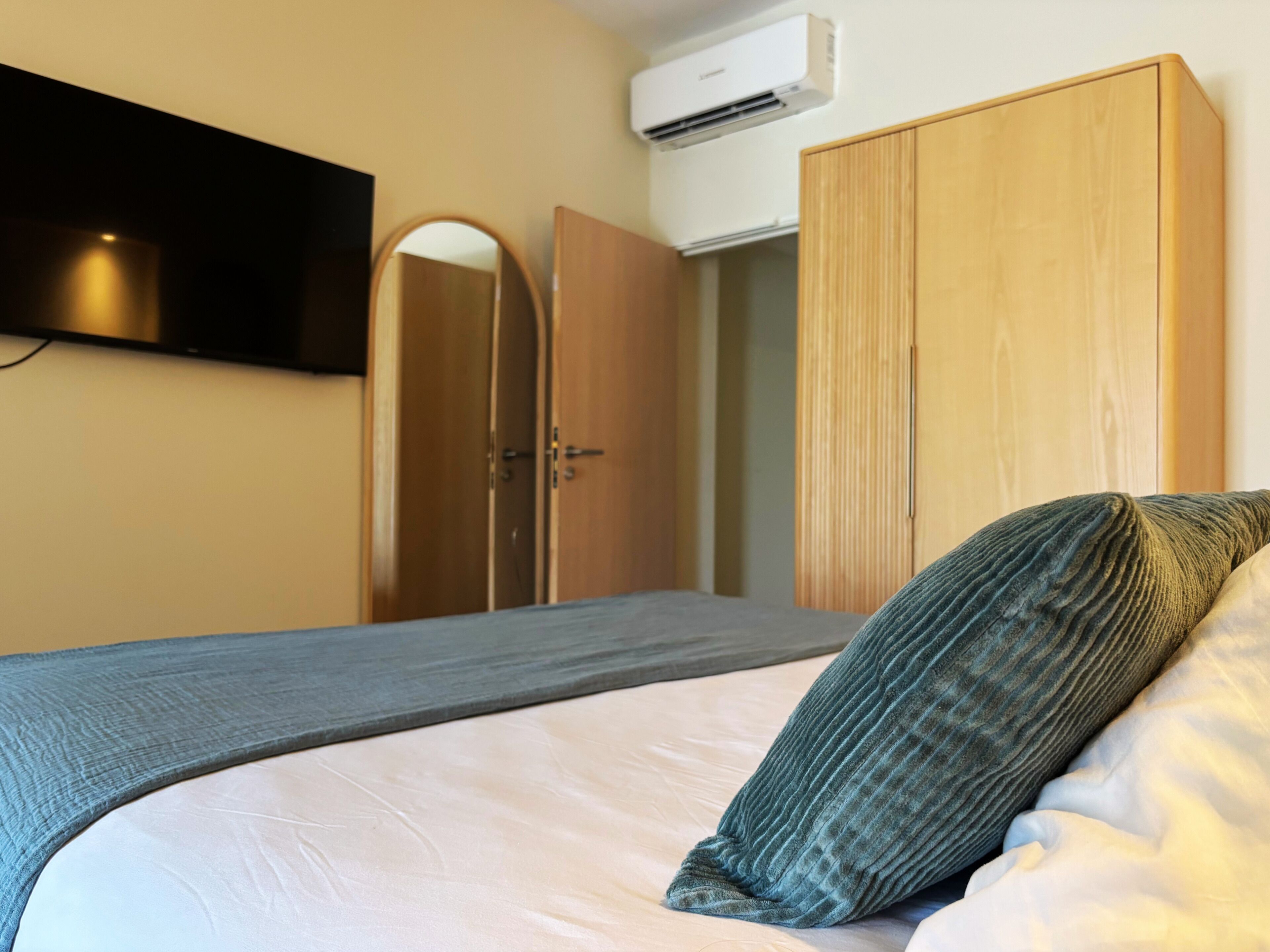 Ein Schlafzimmer mit einem Bett, einem Kleiderschrank, einem Spiegel und einer Klimaanlage.