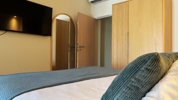 Ein Schlafzimmer mit einem Bett, einem Kleiderschrank, einem Spiegel und einer Klimaanlage.