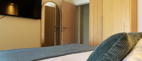 A bedroom with a bed, a wardrobe, a mirror, and an air conditioning unit.