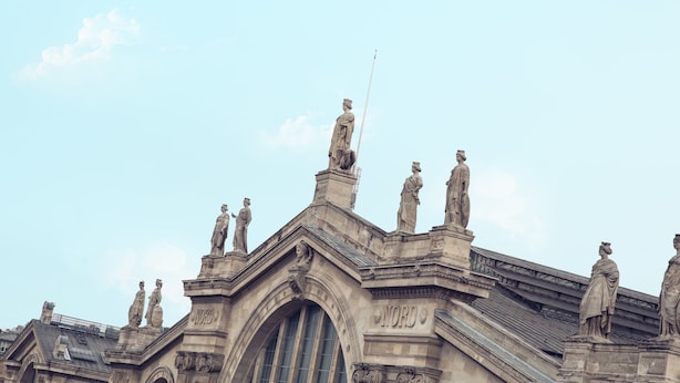 Um edifício histórico com estátuas no telhado e a palavra 'NORD' na fachada.