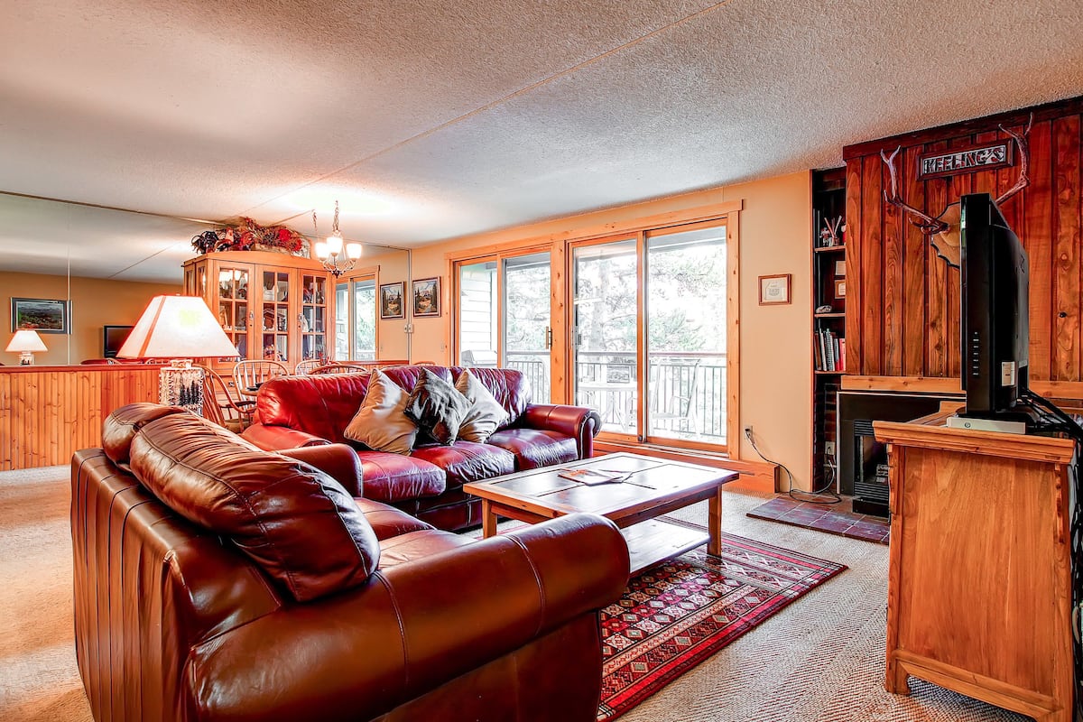 A cozy living room with a leather sofa, wooden cabinets, and a fireplace.