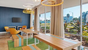 Un comedor moderno con un ventanal grande, una mesa de madera, bancos y sillas amarillas.