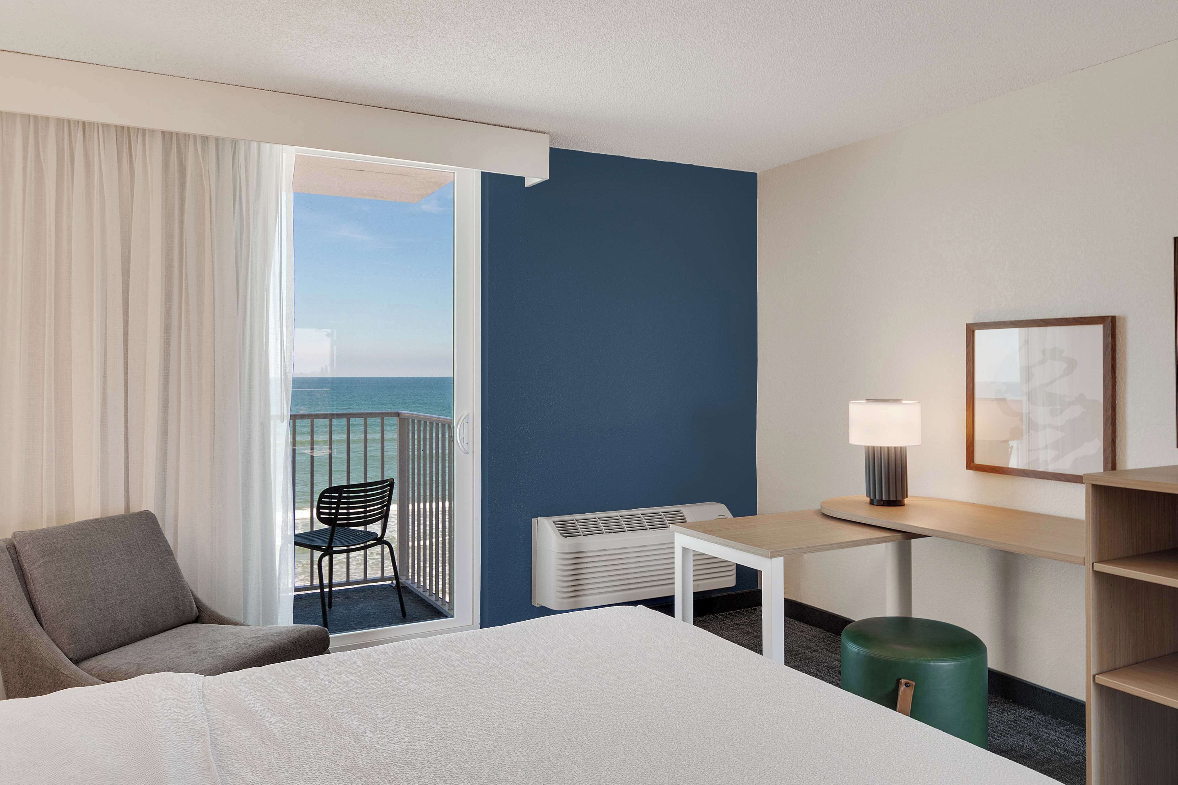 Une chambre d’hôtel avec un lit, un bureau, une chaise, un radiateur et une vue sur l’océan.