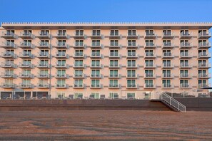 A multi-story hotel with a uniform facade, balconies, and a staircase leading to the entrance. - Spark by Hilton Ormond Beach Oceanfront (Ormond Beach)