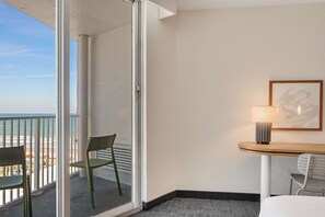 Een hotelkamer met balkon, een tafel met lamp en een bed.